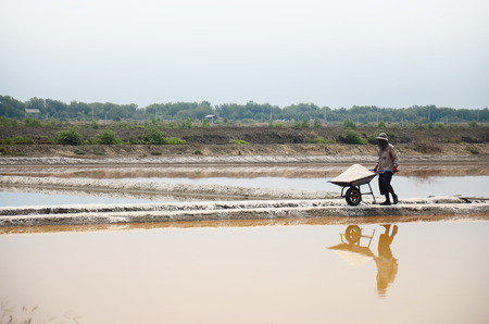 Thai people keeping salt from Salt farming or Salt evaporation pond to warehouse at Bangkhunthein on April 12, 2015 in Bangkok Thailand.のeditorial素材