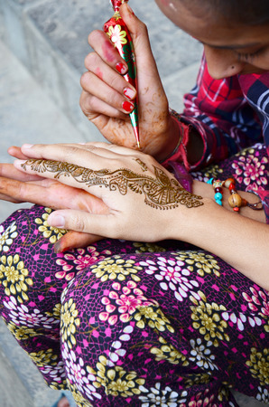 Nepalese girl paint Mehndi or Henna india style for thai traveler women at Thamel market street on October 29, 2013 in Kathmandu, Nepal.のeditorial素材