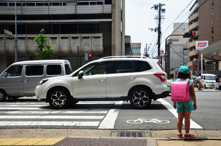 Children japanese girl waiting cross over road at crosswalk traffic road near Gojo subway station on July 11, 2015 in Kyoto, Japanのeditorial素材
