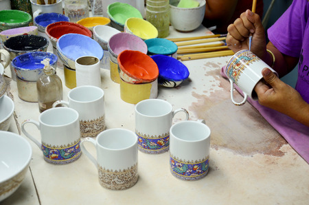 Thai people woking process paint Ceramic Benjarong is traditional thai five basic colors style pottery at workshop on August 8, 2015 in Samutsakhon, Thailand.のeditorial素材