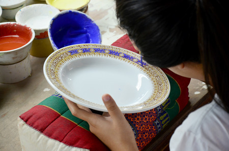 Thai people woking process paint Ceramic Benjarong is traditional thai five basic colors style pottery at workshop on August 8, 2015 in Samutsakhon, Thailand.のeditorial素材