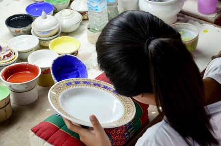 Thai people woking process paint Ceramic Benjarong is traditional thai five basic colors style pottery at workshop on August 8, 2015 in Samutsakhon, Thailand.のeditorial素材
