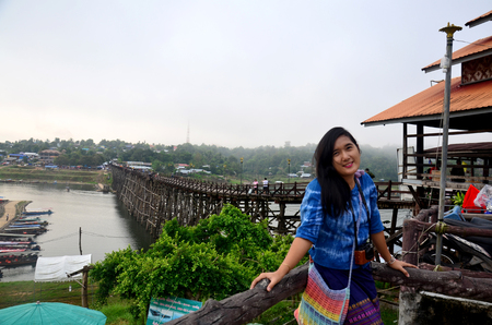 Thai woman travel and portrait on Saphan Mon wooden bridge in morning time at Sangkhlaburi on December 4, 2015 in Kanchanaburi, Thailand.のeditorial素材