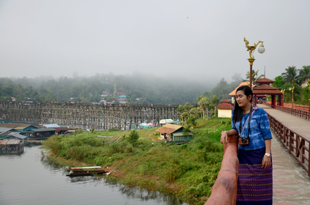 Thai woman travel and portrait on Saphan Mon wooden bridge in morning time at Sangkhlaburi on December 4, 2015 in Kanchanaburi, Thailand.のeditorial素材