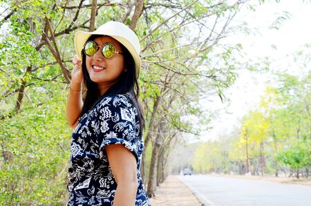 Thai woman portrait and play at outdoor with tree beside road of countryside in Ayutthaya, Thailand