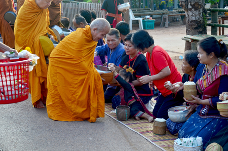 Traditional of almsgiving with sticky rice by Monks procession walk on the road for people put food offerings on January 17, 2016 in Sakon Nakhon, Thailandのeditorial素材