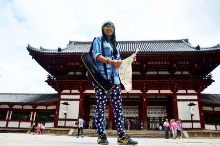 Traveler thai woman holding map and portrait for take photo at front of Todai-ji Temple at Kansai region on July 9, 2015 in Nara, Japanのeditorial素材