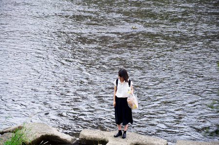 Japanese woman people stand and holding food on stone at riverside of Kamo River on July 11, 2015 in Kyoto, Japanのeditorial素材