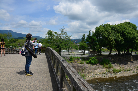Thai woman and Japanese people and traveler foreigner posing for portrait and walking on stone Bridge across the Oi River at Arashiyama on July 12, 2015 in Kyoto, Japanのeditorial素材