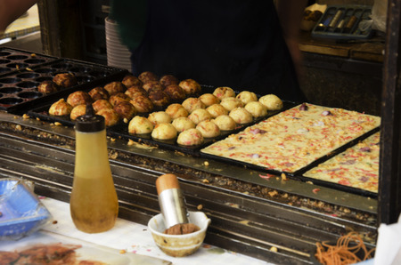 Japanese people cooking takoyaki is a ball-shaped japanese snack for sale at Ameyayokocho market in Ueno district at Tokyo, Japanのeditorial素材