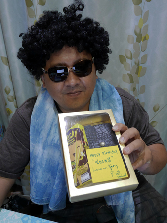 Thai men wear wig and sunglasses holding gift box for my brother birthday at home on November 30, 2016 in Nonthaburi, Thailandのeditorial素材