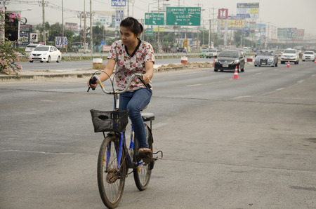 Asian thai woman biking bicycle on street highway with traffic road at Bangbuathong city on February 26, 2017 in Nonthaburi, Thailandのeditorial素材