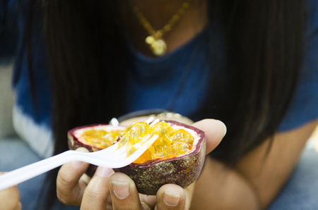 Asian thai woman sit and eating passion fruit at handmade and organic street market fair in Nakhon Ratchasima, Thailand.の写真素材