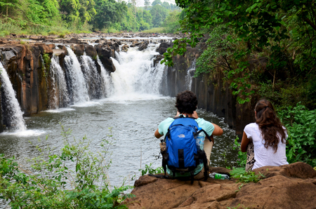 Foreigners travelers lovers sitting and relax on stone at viewpoint of Tad Pha Suam waterfalls on May 2, 2015 in Pakse, Champasak, Laos.のeditorial素材