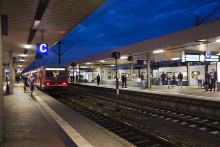 People walk and wait with train running in terminal for send and receive passengers at Mannheim...
