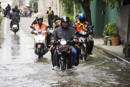 Motorcycle Taxis and volunteer carrying people passed flood on the road go to Bang pai temple join with Royal Cremation on October 26, 2017 in Nonthaburi, Thailandのeditorial素材