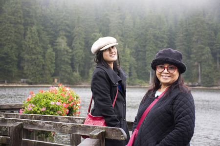 Asain thai women mother and daughter travel and posing at Waterfront wooden bridge at Mummelsee lake while raining in Black Forest or Schwarzwald at Baden-wurttemberg of Stuttgart, Germanyの写真素材