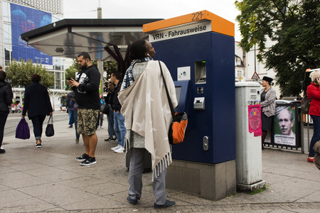 African-German woman buy ticket of tranway from automatic sale ticket box at Heidelberg altstadt or...