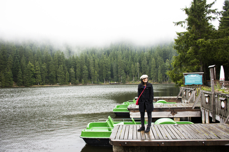 Asian thai woman travel and walking at Waterfront wooden bridge at Mummelsee lake while raining in Black Forest or Schwarzwald at Baden-wurttemberg of Stuttgart, Germanyのeditorial素材