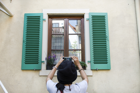 Travelers thai women shooting photo classic retro vintage window on wall of house between visit Ladenburg town at Baden-wurttemberg, Germanyの写真素材