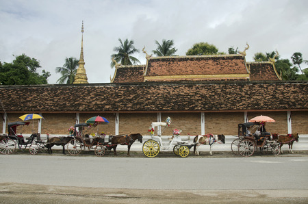Thai people and Horses drawn carriage waiting travelers people use service tour around city at Wat Phra That Lampang Luang temple on July 18, 2017 in Lampang, Thailand のeditorial素材