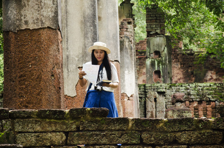 Travelers thai woman walking visit and travel take photo in ancient building and ruins of Kamphaeng Phet Historical Park is an archeological site and Aranyik Area in Kamphaeng Phet, Thailandの写真素材
