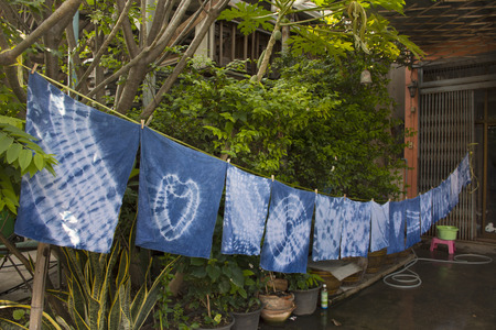 Handkerchief tie batik dyeing tie batik indigo color or mauhom color and hanging process dry clothes in the sun at garden outdoor in Nonthaburi, Thailandの写真素材