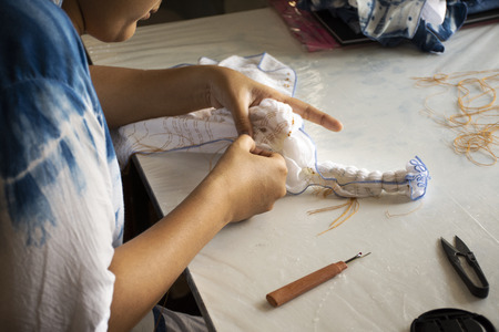 Thai woman people working batik tie dyeing indigo process fold bundle and sewing or arashi shibori...