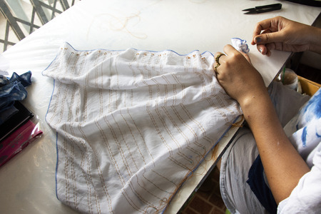 Thai woman people working batik tie dyeing indigo process fold bundle and sewing or arashi shibori on fabric at workshop on April 20, 2018 in Nonthaburi, Thailandのeditorial素材