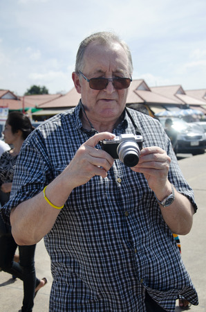 German old man travel and using camera take photo at outdoor of Ang Sila Fishing village and seafood Market on January 2, 2017 in Chonburi, Thailandのeditorial素材