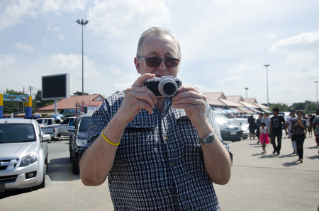 German old man travel and using camera take photo at outdoor of Ang Sila Fishing village and seafood Market on January 2, 2017 in Chonburi, Thailandのeditorial素材