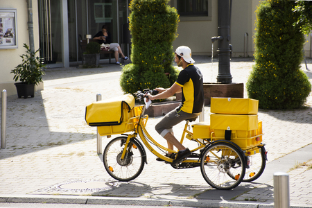 German people biking bicycle three wheels and cart send newspaper and brochure to house on road at Sandhausen district village on August 25, 2017 in Heidelberg, Germanyのeditorial素材