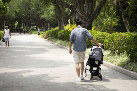 Chinese man people pushing cart and baby on the road in garden at Zhongshan public park in Shantou city or Swatow city on May 9, 2018 in Guangdong, Chinaの写真素材