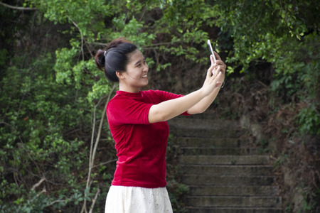 Traveler thai woman use smartphone selfie take photo at view point of Queshi Scenic Area at Shantou town or Swatow city on May 7, 2018 in Chaozhou, Chinaの写真素材