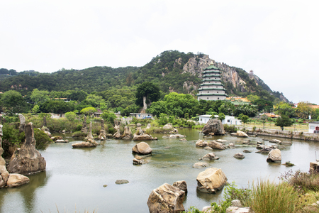 View landscape with stone and rock water garden of Tiantan temple and chedi in Tian Tan Garden with meadow and mountain at Shantou or Swatowの写真素材