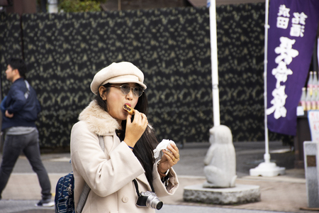 Tokyo, Japan - March 31, 2019 :  Traveler thai women travel visit and eating local japanese snacks food in street market of Naritasan Omote Sando or Narita old town at Chiba on March 31, 2019 in Tokyo, Japanのeditorial素材