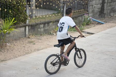 Thai boy biking bicycle on street of small village at countryside in Yasothon, Thailandの写真素材