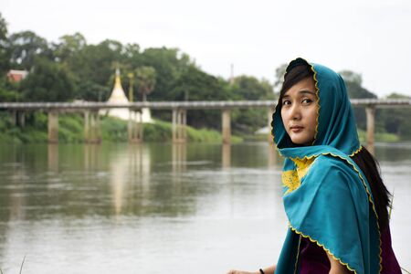Travelers thai women alone wearing clothes mon ethnic style for take photo lonely at riverside of Mae Khlong or Meklong river at Ban Pong in evening in Ratchaburi, Thailandの写真素材