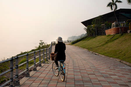 MUKDAHAN, THAILAND - OCTOBER 2 : Thai women biking bicycle on street at riverside Mekhong river in evening at Mukdahan city on October 2, 2019 in Mukdahan, Thailandのeditorial素材