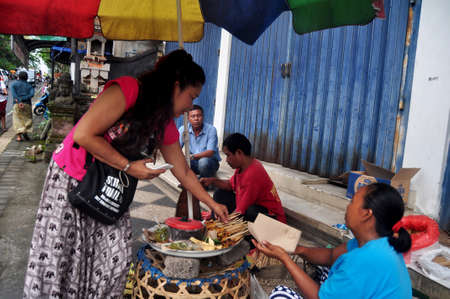BALI, INDONESIA - MARCH 22 : Indonesian people and foreigner travelers buying and taste eats local street food Bali style from hawker restaurant at Ubud Market on March 22, 2018 in Bali, Indonesiaのeditorial素材