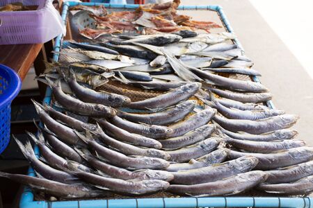 Dried sun fish for food preserves on wire sieve at outdoor for sale customer in local market shop of...