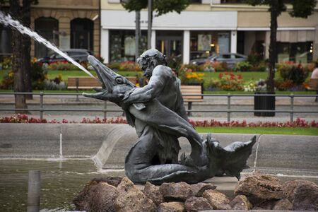 Art mermaid man and waterspout fish statue of water fountain in Mannheimer Wasserturm Water tower gardens in Friedrichsplatz square at Mannheim city on September 9, 2019 in Baden-Wurttemberg, Germanyの写真素材