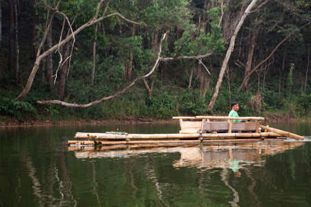 Thai rower waterman rowing bamboo rafts in Pang Ung lake for service travelers people travel visit...