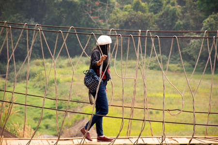 Travelers thai women visit walking on wooden suspension bridge in Pang Ung lake in Pang Oung forest park or Switzerland of Thailand in authentic Chinese village Ban Rak Thai in Mae Hong Son, Thailandのeditorial素材