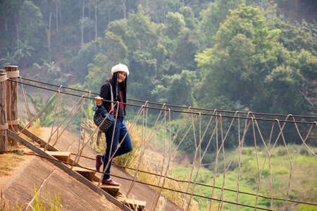 Travelers thai women visit walking on wooden suspension bridge in Pang Ung lake in Pang Oung forest park or Switzerland of Thailand in authentic Chinese village Ban Rak Thai in Mae Hong Son, Thailandのeditorial素材