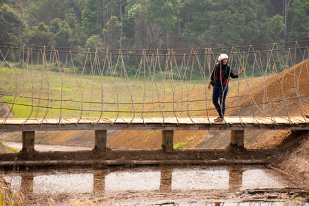 Travelers thai women visit walking on wooden suspension bridge in Pang Ung lake in Pang Oung forest park or Switzerland of Thailand in authentic Chinese village Ban Rak Thai in Mae Hong Son, Thailandのeditorial素材