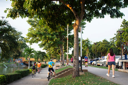 Asian thai people and foreign travelers walking jogging exercise  biking bicycle on pathway around pondside in dusk time at Nong Prajak public garden park on September 15, 2020 in Udon Thani, Thailandのeditorial素材