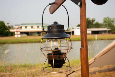 Antique retro vintage Kerosene lamp or burning oil lantern on pole for tent camping on grass park beside irrigation canal at Bangbuathong city rural countryside of Nonthaburi in Nonthaburi, Thailandの写真素材