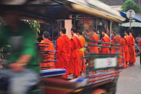 Tradition of almsgiving with sticky rice by Monks laotian procession walk on the road for Lao people and foreign travelers put food offerings at Wat xieng thong on April 9, 2016 in Luang Prabang, Laosのeditorial素材