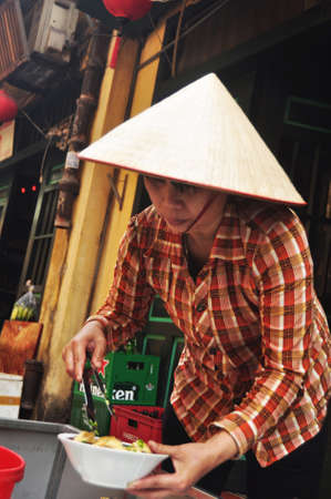 Vietnam woman people cooking local vietnamese food and sale to vietnamese people and foreign travelers travel visit on Hang Buom walking street at Hoan Kiem city on April 12, 2016 in Hanoi, Vietnamのeditorial素材